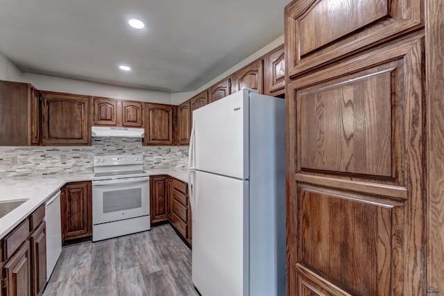 kitchen with hardwood / wood-style floors, white appliances, and decorative backsplash