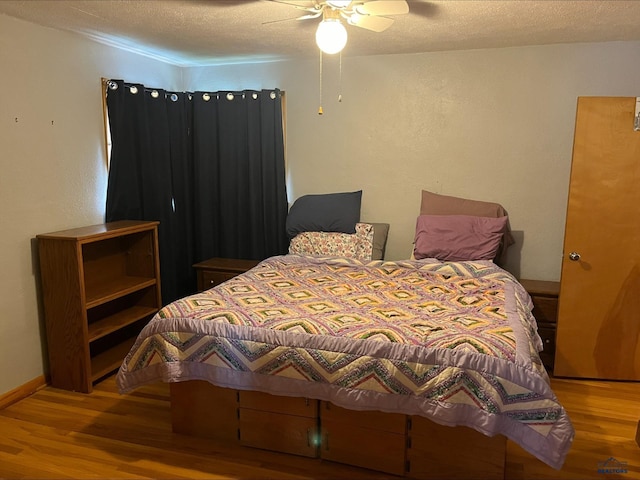 bedroom featuring a textured ceiling, wood-type flooring, and ceiling fan