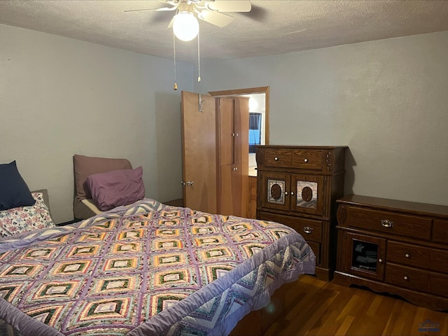 bedroom with ceiling fan, dark hardwood / wood-style flooring, and a textured ceiling