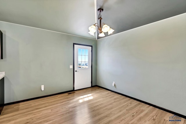 empty room featuring a chandelier and light hardwood / wood-style floors