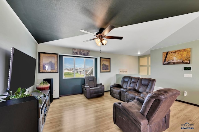 living room featuring light wood-type flooring, ceiling fan, a textured ceiling, and vaulted ceiling