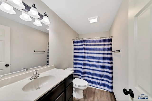 bathroom featuring a shower with curtain, wood-type flooring, toilet, and vanity