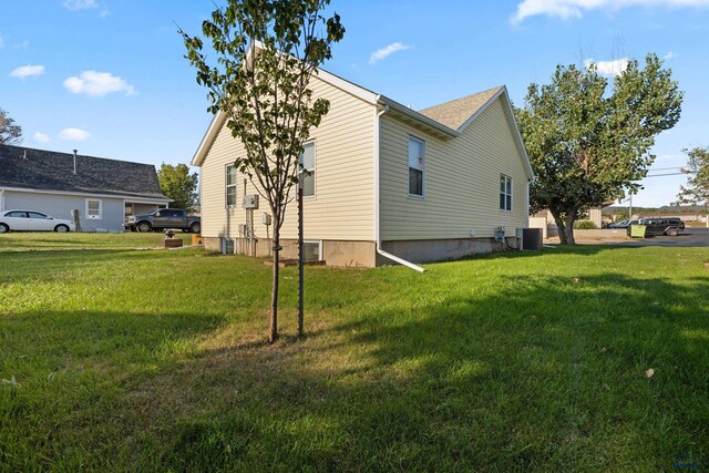 view of side of property featuring a yard and central AC