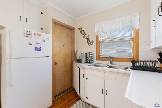 kitchen with wood-type flooring, crown molding, sink, white cabinetry, and white refrigerator