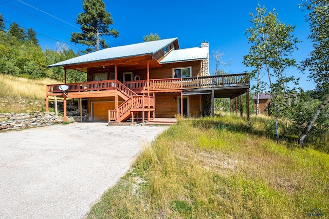 21169 Last Chance Trl, Lead, SD 57754 - rustic home with a chimney, gravel driveway, a wooden deck, an attached garage, and metal roof