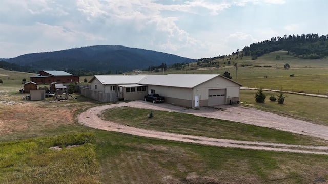 view of side of property with a mountain view, a lawn, a garage, and a rural view