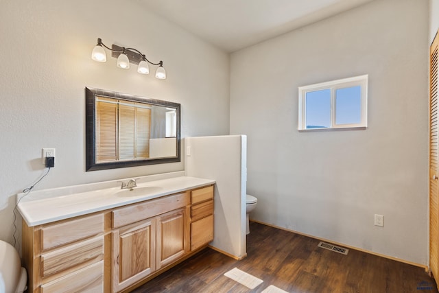 bathroom with wood-type flooring, toilet, and vanity