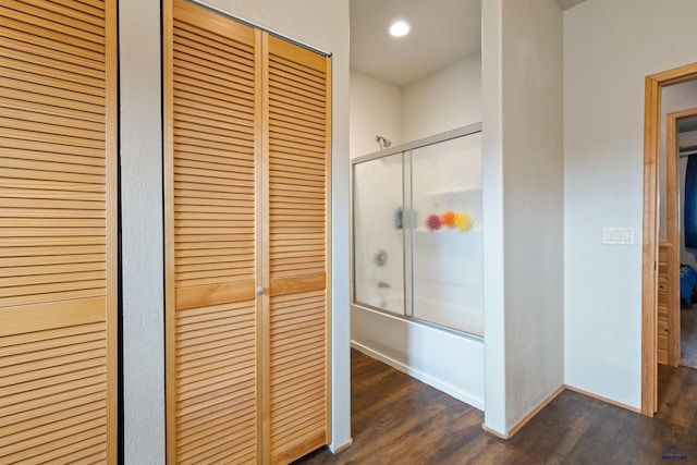 bathroom featuring hardwood / wood-style flooring and bath / shower combo with glass door