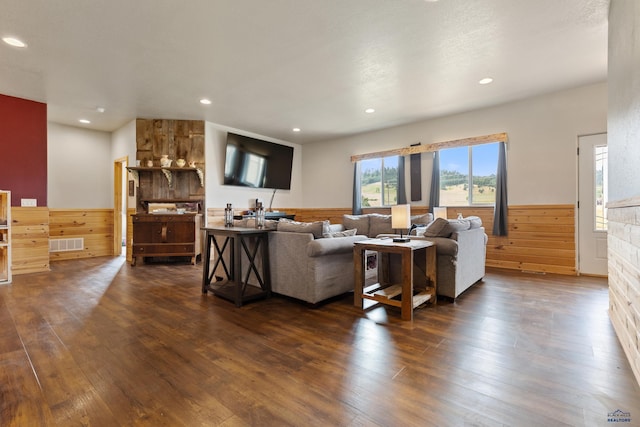 living room with dark wood-type flooring and wood walls