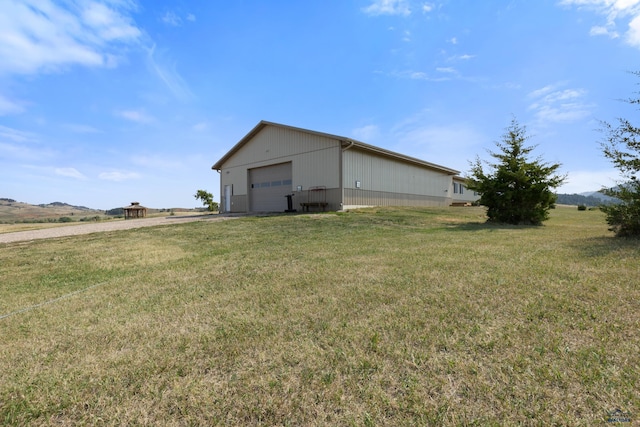 view of yard featuring an outdoor structure, a rural view, and a garage