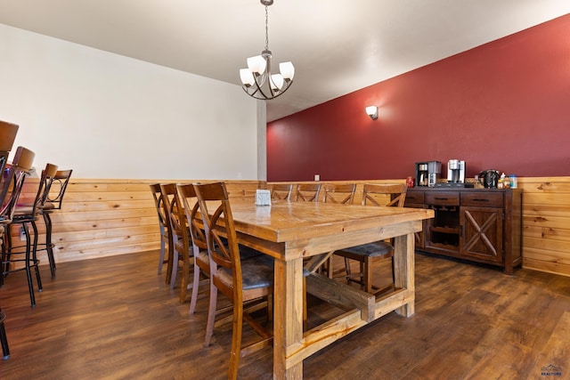 dining space featuring wood walls, a notable chandelier, and dark hardwood / wood-style floors