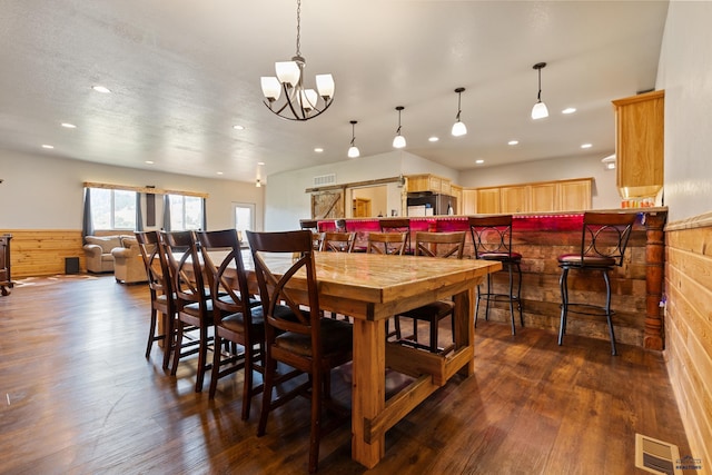 dining room with dark hardwood / wood-style floors, an inviting chandelier, and wooden walls