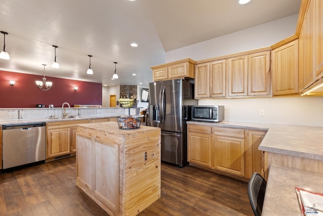 kitchen with wood counters, appliances with stainless steel finishes, sink, kitchen peninsula, and a kitchen island