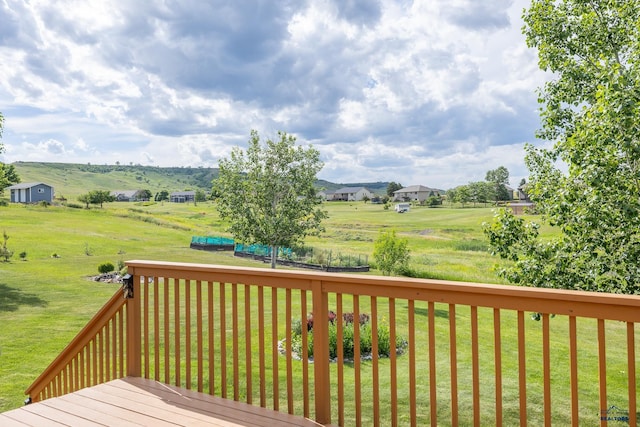 wooden terrace with a yard and a rural view