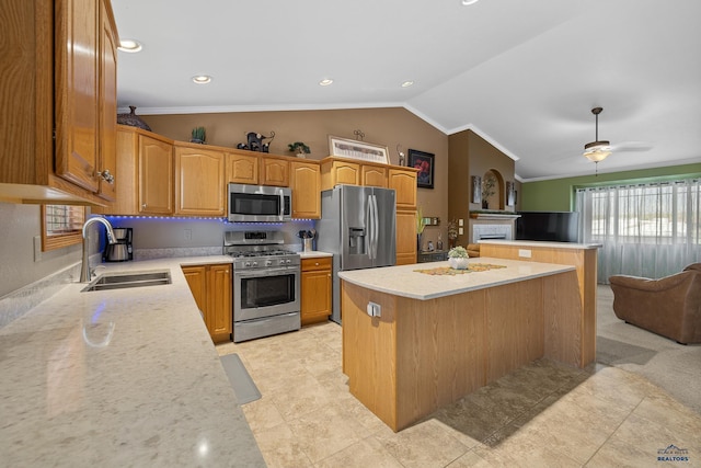 kitchen with vaulted ceiling, appliances with stainless steel finishes, sink, ceiling fan, and a kitchen island