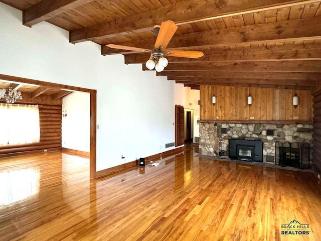 unfurnished living room featuring beamed ceiling, light hardwood / wood-style flooring, ceiling fan, a stone fireplace, and wood ceiling