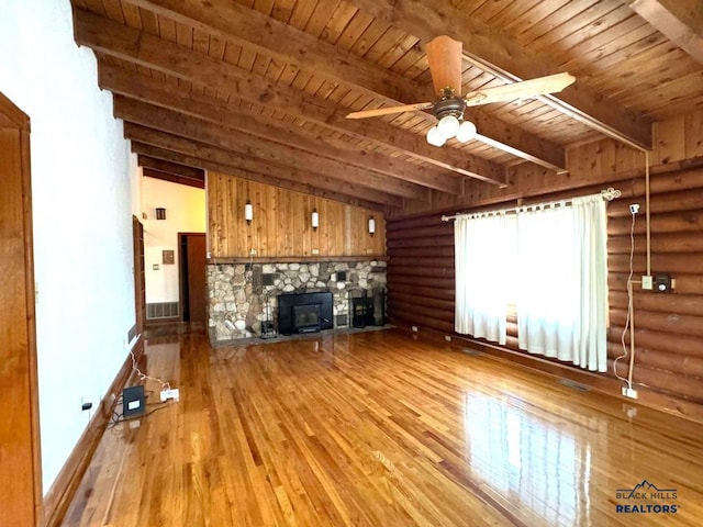 unfurnished living room featuring wooden ceiling, light hardwood / wood-style floors, beamed ceiling, a stone fireplace, and ceiling fan