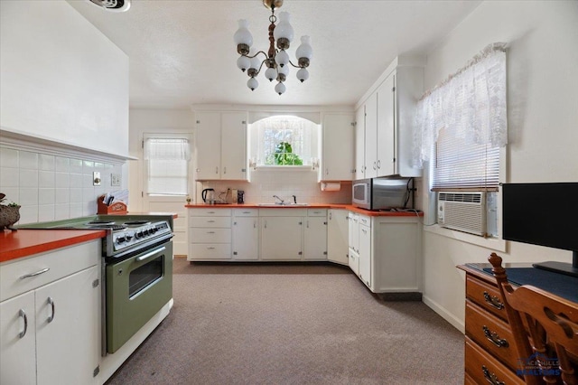 kitchen with an inviting chandelier, white cabinets, stove, and decorative backsplash