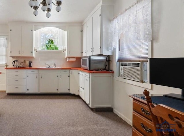 914 Kingsbury St, Belle Fourche, SD 57717 - kitchen featuring a sink, stainless steel microwave, white cabinetry, and a chandelier