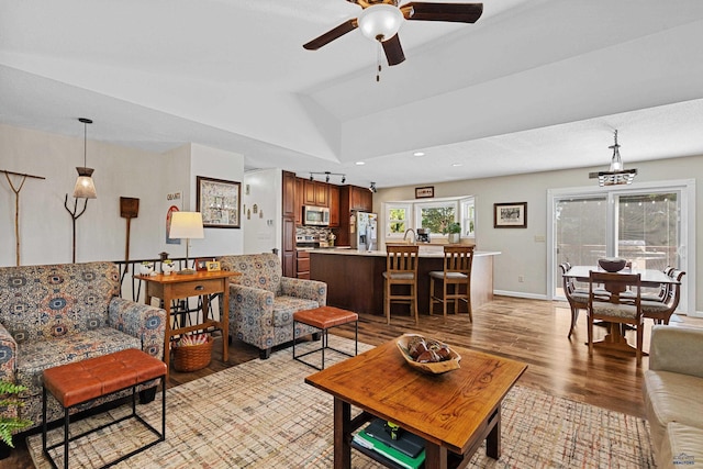 living room with ceiling fan, vaulted ceiling, a healthy amount of sunlight, and light hardwood / wood-style flooring