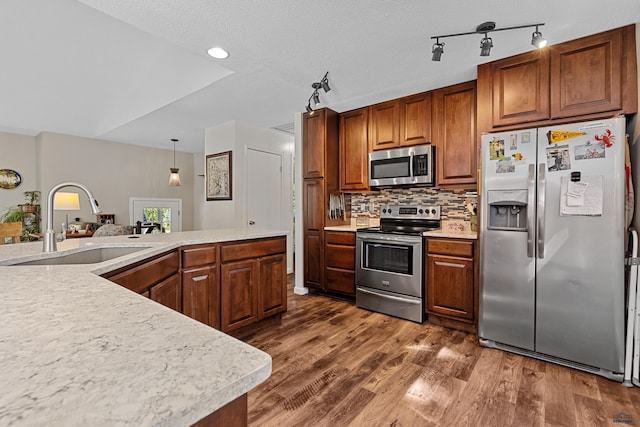 kitchen featuring stainless steel appliances, sink, dark hardwood / wood-style floors, backsplash, and decorative light fixtures