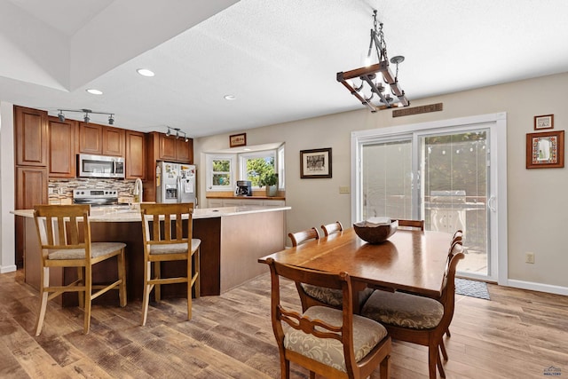 dining space featuring light hardwood / wood-style floors, a notable chandelier, and a textured ceiling