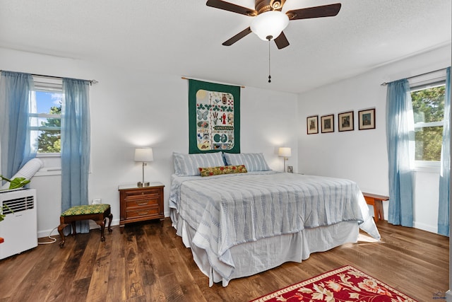 bedroom featuring multiple windows, dark hardwood / wood-style flooring, and ceiling fan