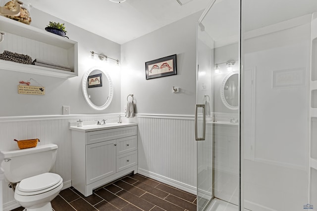 bathroom with a shower with door, vanity, and toilet