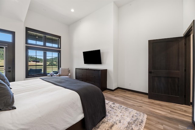 bedroom with light wood-type flooring and a towering ceiling