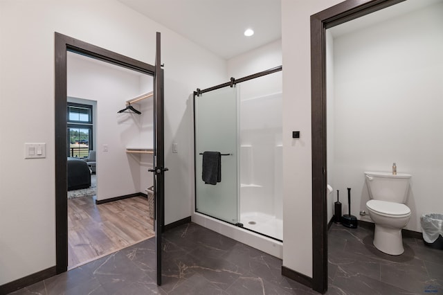 bathroom featuring walk in shower, toilet, and wood-type flooring