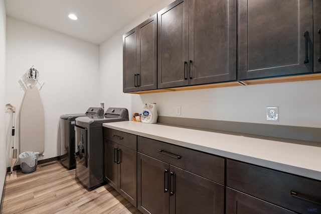 laundry room featuring washer and clothes dryer, cabinets, and light hardwood / wood-style floors