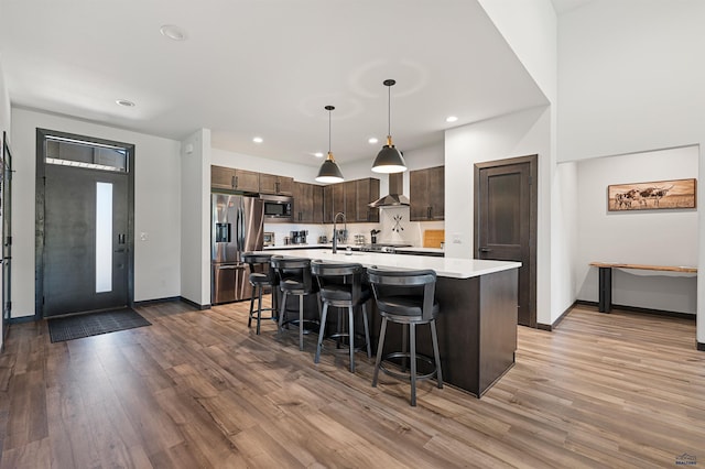 kitchen featuring dark brown cabinets, stainless steel appliances, pendant lighting, and hardwood / wood-style flooring