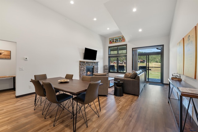 dining space with a towering ceiling, hardwood / wood-style flooring, and a fireplace