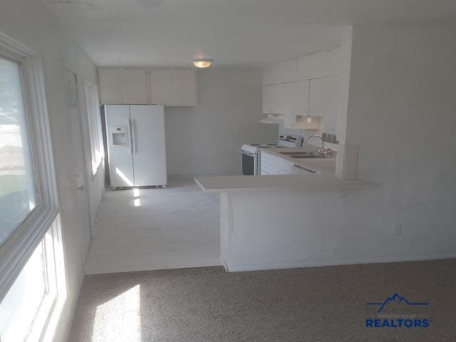 kitchen with white appliances, kitchen peninsula, white cabinetry, and sink