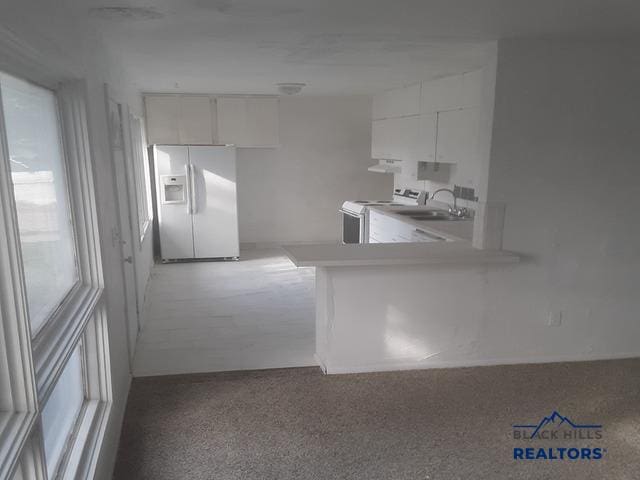 kitchen featuring washer / clothes dryer, white cabinetry, white appliances, kitchen peninsula, and sink