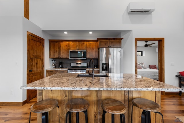 23974 Thompson Dr, Hill City, SD 57745 - kitchen featuring stainless steel appliances, a wall mounted AC, light wood finished floors, backsplash, and a ceiling fan
