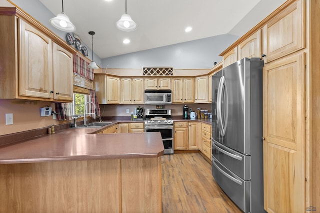 kitchen with vaulted ceiling, appliances with stainless steel finishes, decorative light fixtures, and sink