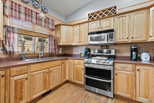 kitchen featuring appliances with stainless steel finishes, lofted ceiling, sink, and light hardwood / wood-style flooring