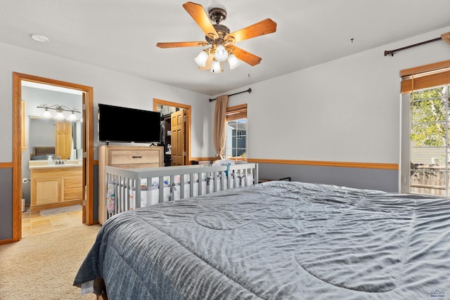 bedroom with ceiling fan, light colored carpet, and ensuite bathroom