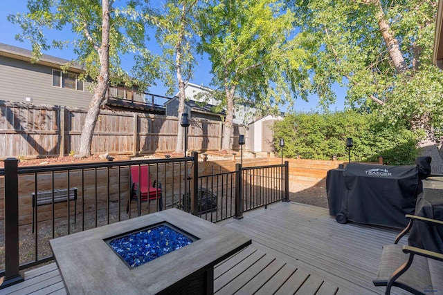 wooden terrace featuring a grill and a fire pit