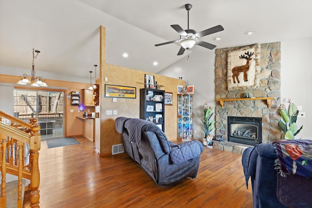 living room featuring ceiling fan with notable chandelier, vaulted ceiling, a fireplace, and hardwood / wood-style floors