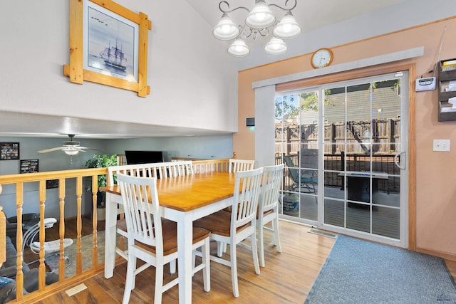 dining room featuring ceiling fan with notable chandelier, vaulted ceiling, and hardwood / wood-style flooring