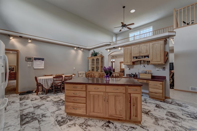 11845 N Haines Ave, Rapid City, SD 57701 - kitchen featuring a towering ceiling, dark countertops, ceiling fan, marble finish floor, and light brown cabinetry