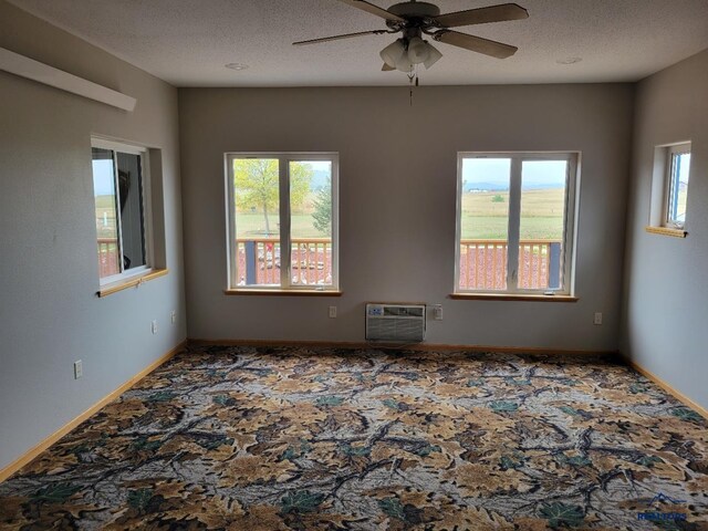 11845 N Haines Ave, Rapid City, SD 57701 - spare room featuring an AC wall unit, a textured ceiling, a ceiling fan, and carpet floors