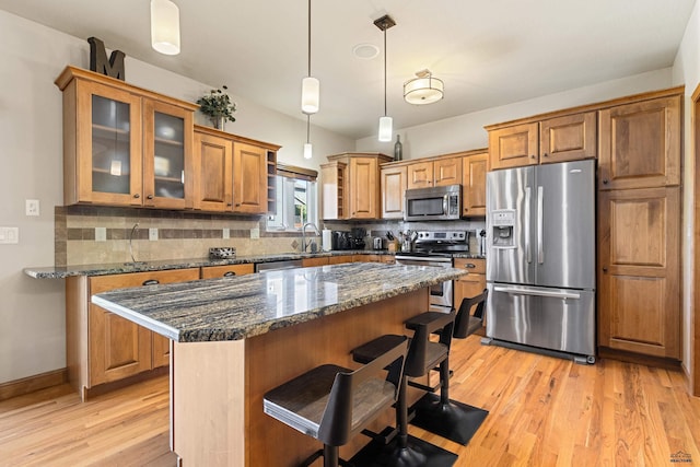 kitchen with dark stone countertops, a center island, light hardwood / wood-style floors, and appliances with stainless steel finishes