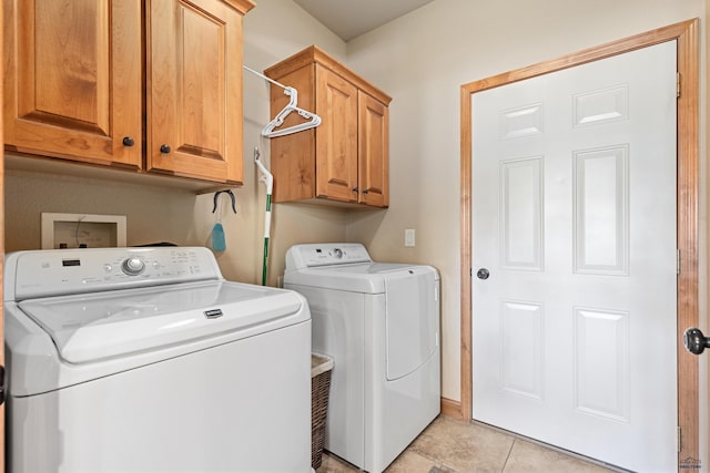 laundry room with cabinets, light tile patterned floors, and washer and dryer