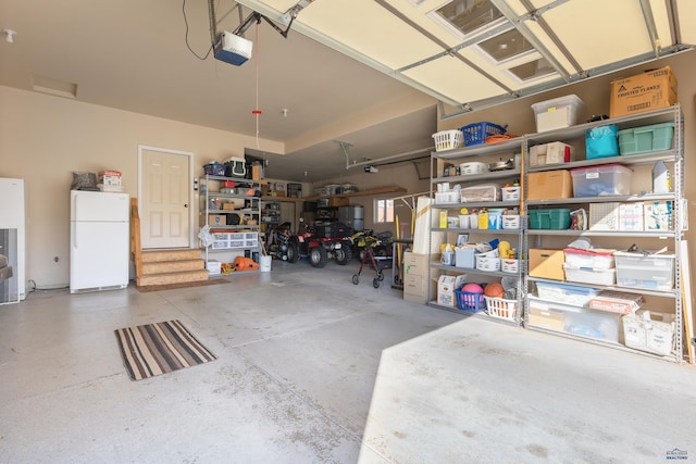 garage with a garage door opener and white refrigerator