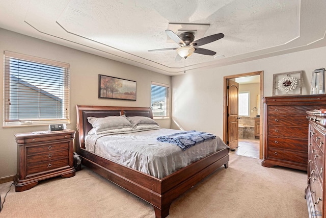 carpeted bedroom with multiple windows, ensuite bathroom, ceiling fan, and a textured ceiling