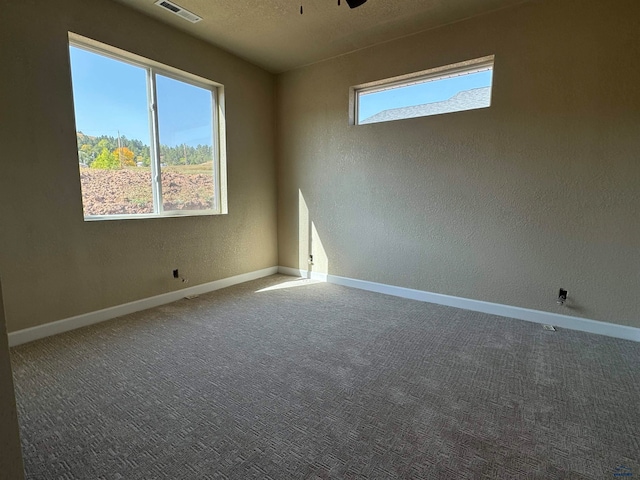 empty room featuring baseboards, a textured wall, carpet flooring, a ceiling fan, and a textured ceiling