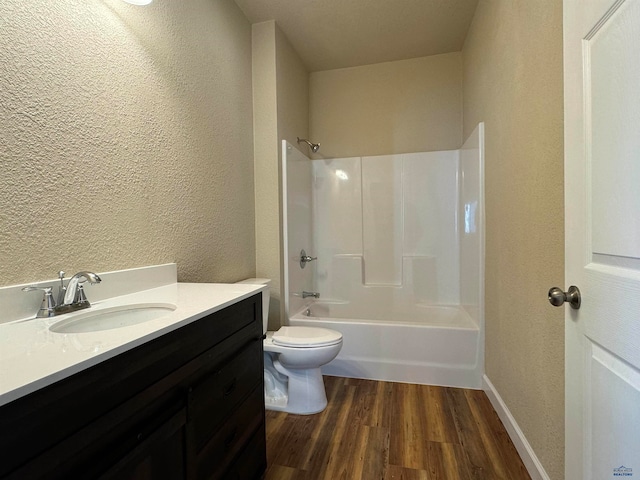 bathroom with a textured wall, wood finished floors, vanity, toilet, and  shower combination
